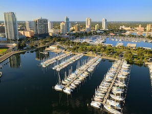 A marina with numerous boats docked, surrounded by a cityscape with high-rise buildings.