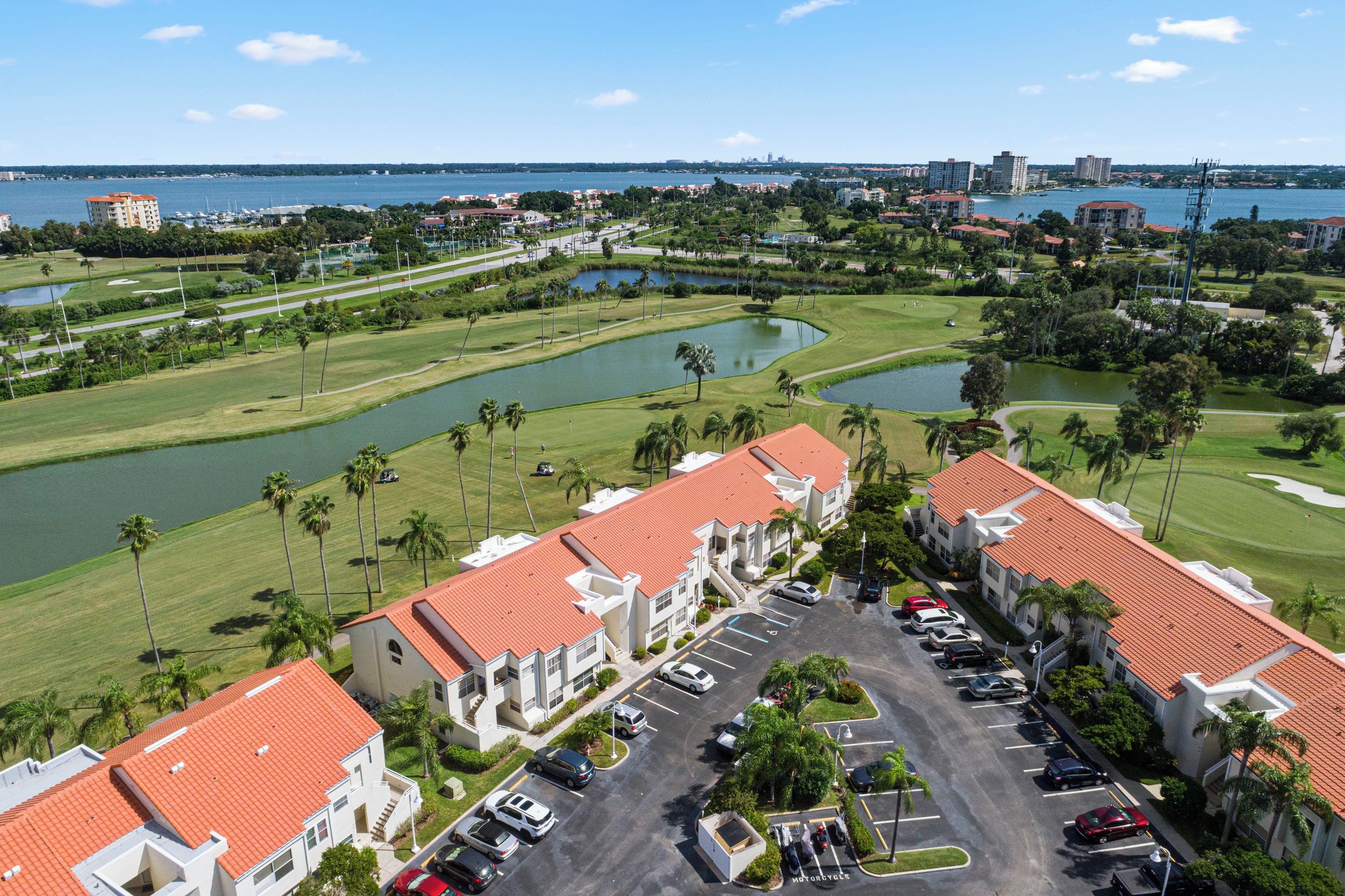A hotel with red-tiled roofs, a parking lot, and a golf course with water hazards.