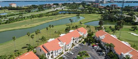 A hotel with red-tiled roofs, a parking lot, and a golf course with water hazards.