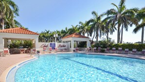 A swimming pool with lounge chairs and a gazebo, surrounded by palm trees. - Bahia Vista 17-881 by Distinctive Beach Rentals (St. Petersburg)