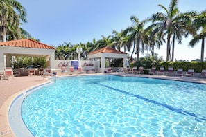A swimming pool with lounge chairs and a gazebo, surrounded by palm trees. - Bahia Vista 17-881 by Distinctive Beach Rentals (St. Petersburg)