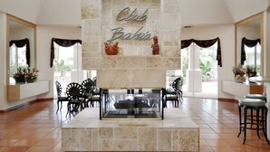 A spacious lobby with a stone fireplace, a sign reading "Club Bahia", and a seating area with chairs and a table. - Bahia Vista 17-881 by Distinctive Beach Rentals (St. Petersburg)