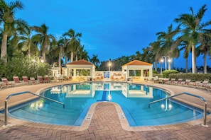 Ein Pool mit Liegestühlen und Palmen.