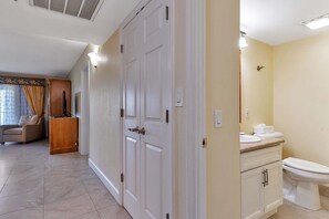 A hotel room with a large wardrobe, a television, a sofa, and a bathroom with a toilet and sink.