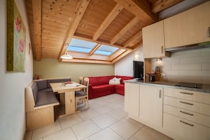 A compact kitchen with a dining area, a red sofa, and a skylight.