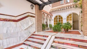 Un patio con escalones de mármol, paredes de ladrillo y plantas en macetas.