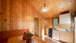 Un intérieur en bois comprenant un coin cuisine, une table à manger agrémentée d’un centre de table floral et un banc.