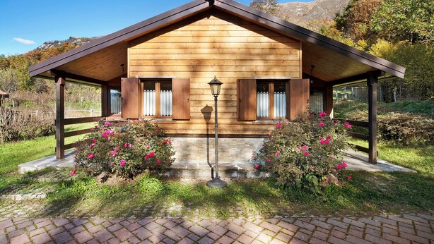 Une cabane en bois avec un toit à deux versants, une lanterne et un chemin de briques menant à l’entrée.