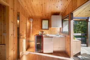 Un interior de madera con kitchenette, una ventana con cortinas y una puerta que conduce a otra habitación.