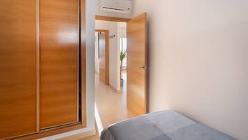 A bedroom with a bed, wooden wardrobe, and an air conditioning unit.
