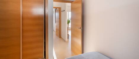 A bedroom with a bed, wooden wardrobe, and an air conditioning unit.