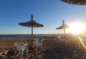 A beach with thatched umbrellas and white plastic chairs. - Apartment 'Luxury with Stunning Views' with Mountain View, Pool, Terrace & Garden (Condado de Alhama - Polaris World)