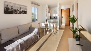 Een modern interieur met een bank, eettafel, stoelen, een keukenhoek en een potplant.