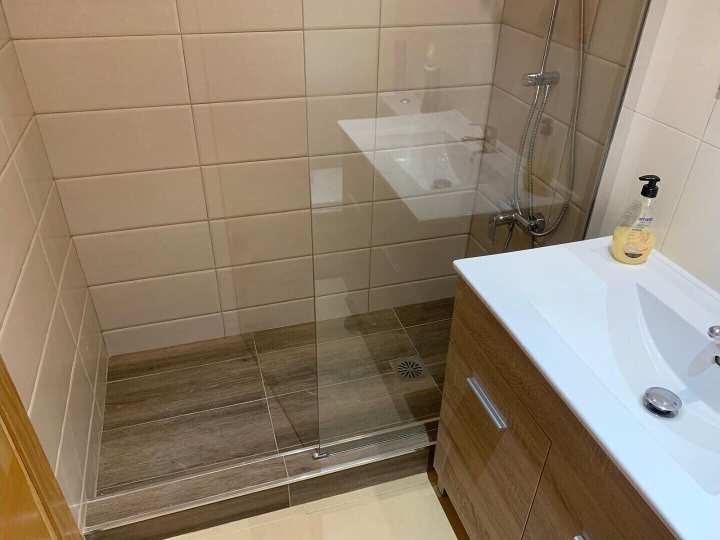 Ein Badezimmer mit Dusche, Waschbecken und einer Seife auf der Ablagefläche.