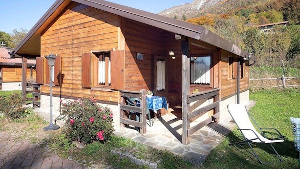 Eine Holzhütte mit Veranda, Steintreppe und Tisch mit Stühlen.