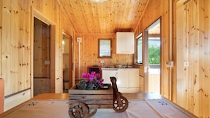 Ein Holzblockhaus-Interieur mit Esstisch, einem Holzwagen und einem Fenster mit Blick.