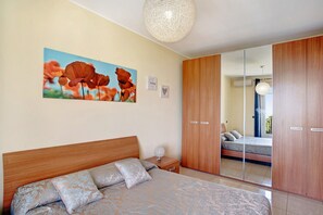 Un dormitorio con cama, mesita de noche, espejo y armario de madera.