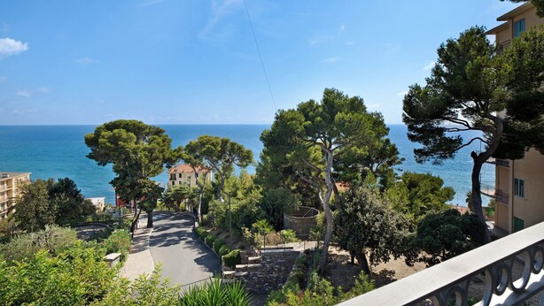 Eine Küstenstraße mit Gebäuden, Bäumen und Blick aufs Meer.