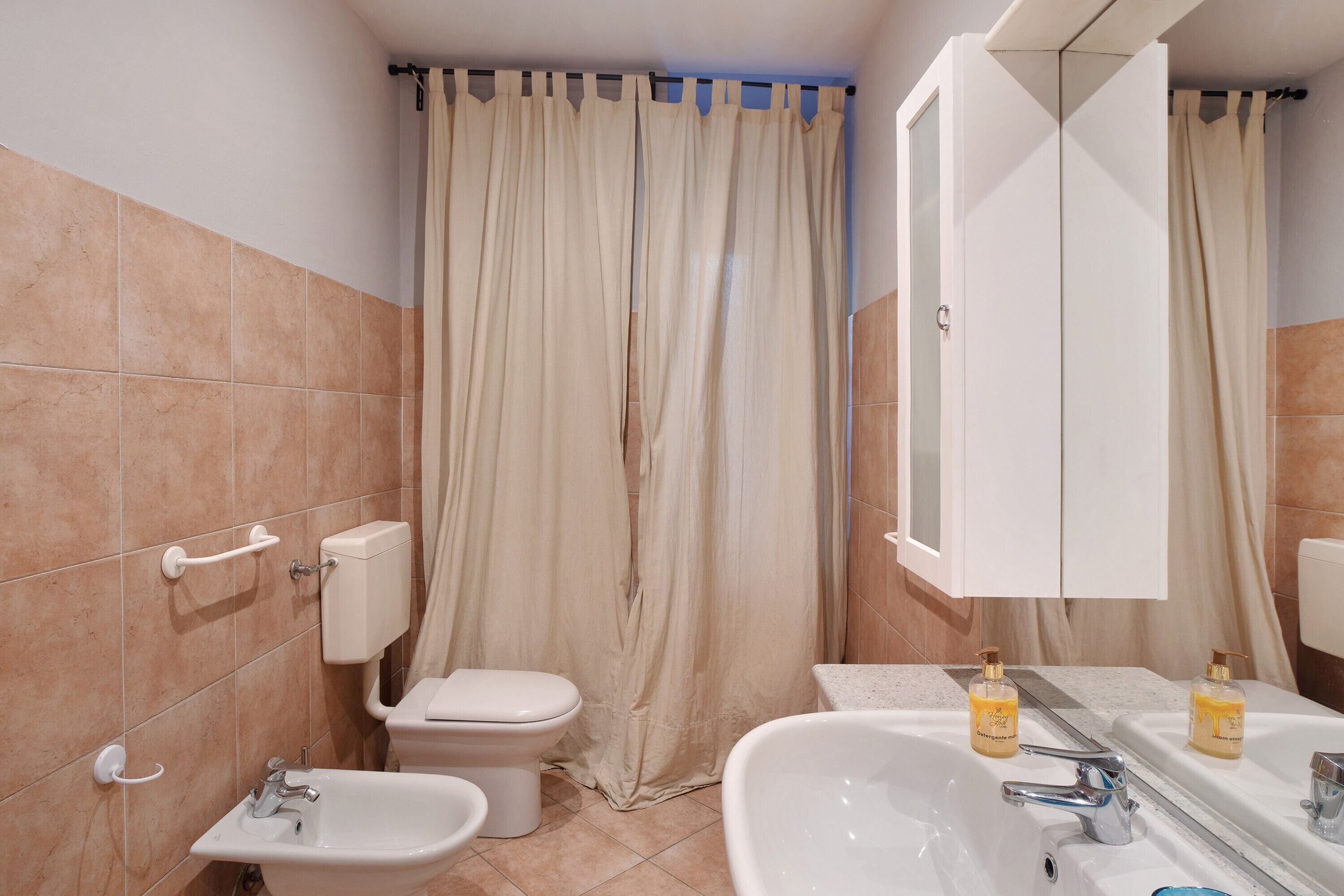 A bathroom with a toilet, bidet, sink, and mirror.