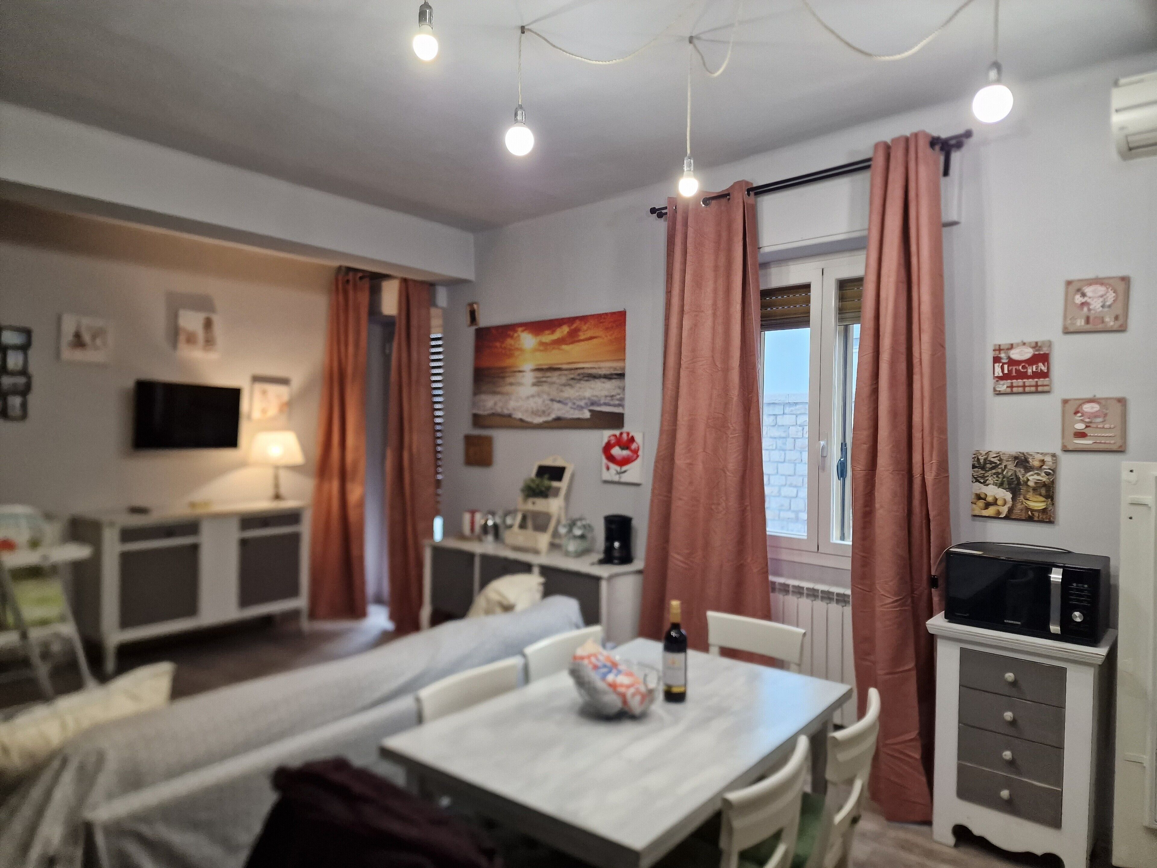 A small, well-lit room with a dining table, chairs, a TV, and a microwave.