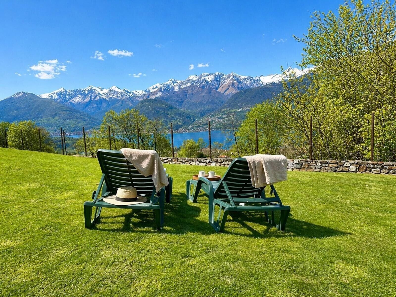 Dos sillones con toallas, una mesita y vistas a montañas y un lago.