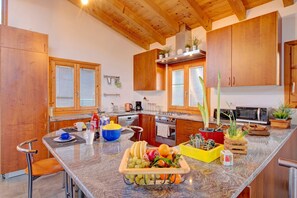 Une cuisine moderne avec des meubles en bois, un plan de travail en granit et divers appareils de cuisine.