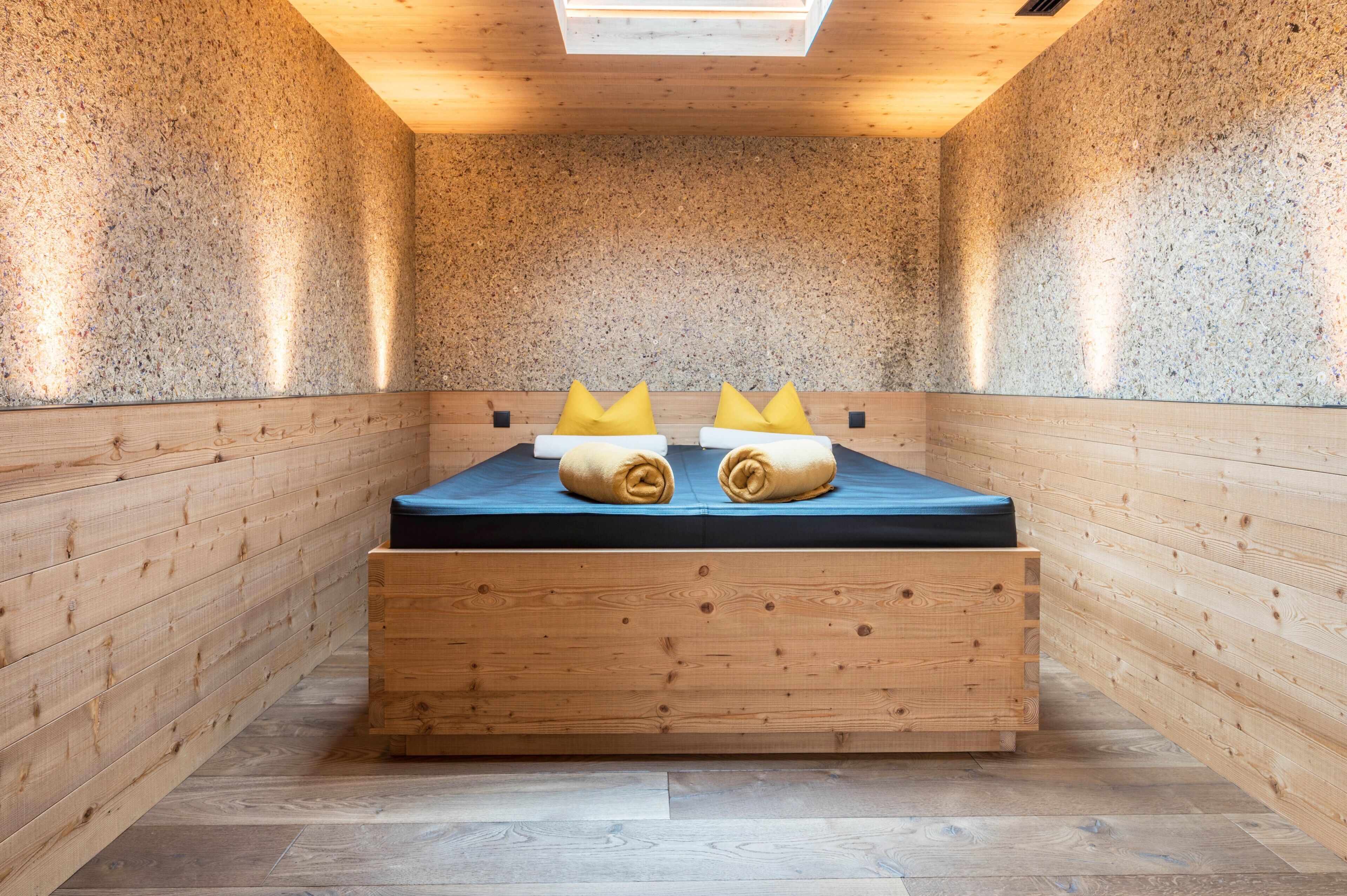 Une pièce en bois avec un lit, des oreillers et un luminaire au plafond.