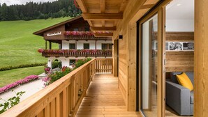 Un balcon en bois offrant une vue sur un champ verdoyant et un bâtiment portant l’inscription « Wodachhof ».