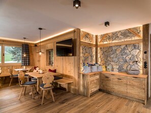 Un intérieur en bois agrémenté d’un mur en pierre, un coin repas avec des chaises et une table, et un meuble intégré doté de tiroirs.