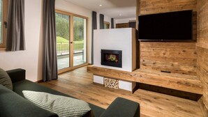 Una sala de estar moderna con chimenea, televisor de pantalla plana y puerta corrediza de vidrio que da a un balcón.