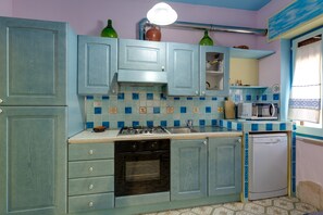 A kitchen with blue cabinets, a stove, an oven, a microwave, and a dishwasher.