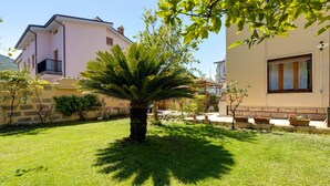 Een woonhuis met een verzorgd gazon, een palmboom en een huis met balkon.