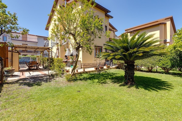 A residential building with a covered patio, a lawn, and a palm tree.