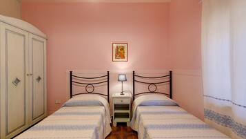 Una camera da letto con due letti, un armadio, un comodino con una lampada e un quadro appeso al muro.