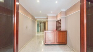Un passadís amb sòl de marbre, una taquilla de fusta i una porta al final.