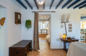 Une pièce comprenant un lit, une commode en bois, une table avec une lampe, une plante et une horloge murale.
