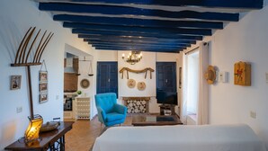 Un dormitorio con una cama, un sillón azul, un televisor y una chimenea.