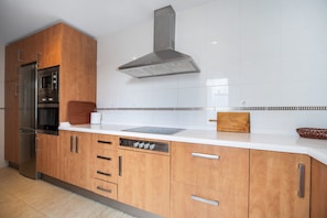 A modern kitchen with wooden cabinets, stainless steel appliances, and a white tiled backsplash.