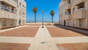 Un cortile con pavimento piastrellato, due palme e un lampione.