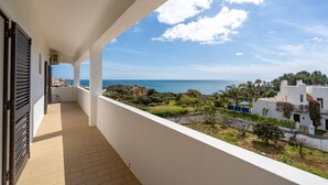 En balkon med havudsigt og en hvid bygning med have.