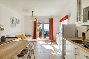 Una cocina moderna con comedor, vistas al exterior y un balcón con cortinas naranjas.