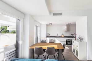 A modern kitchen with white cabinets, a wooden dining table, and a bicycle on the counter. - Vacation Home "Casa Bos Dolphin Pool Jacuzzi 6P" with Wi-Fi, A/C, Balcony, Terrace & Garden (Gran Alacant - Santa Pola)