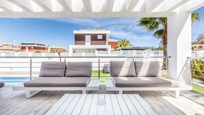Una terrazza panoramica sul tetto con piscina, due divani e vista sugli edifici.
