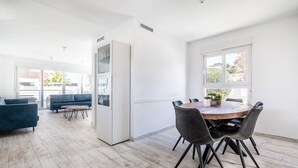 Un soggiorno moderno con un divano blu, un tavolo da pranzo in legno e sedie, e un'ampia finestra.