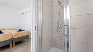 Een moderne kamer met een bed, een douche en een deur naar een andere kamer.