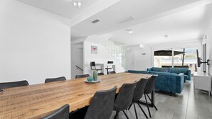 Een moderne eethoek met een houten tafel, zwarte stoelen en een blauwe bank op de achtergrond.