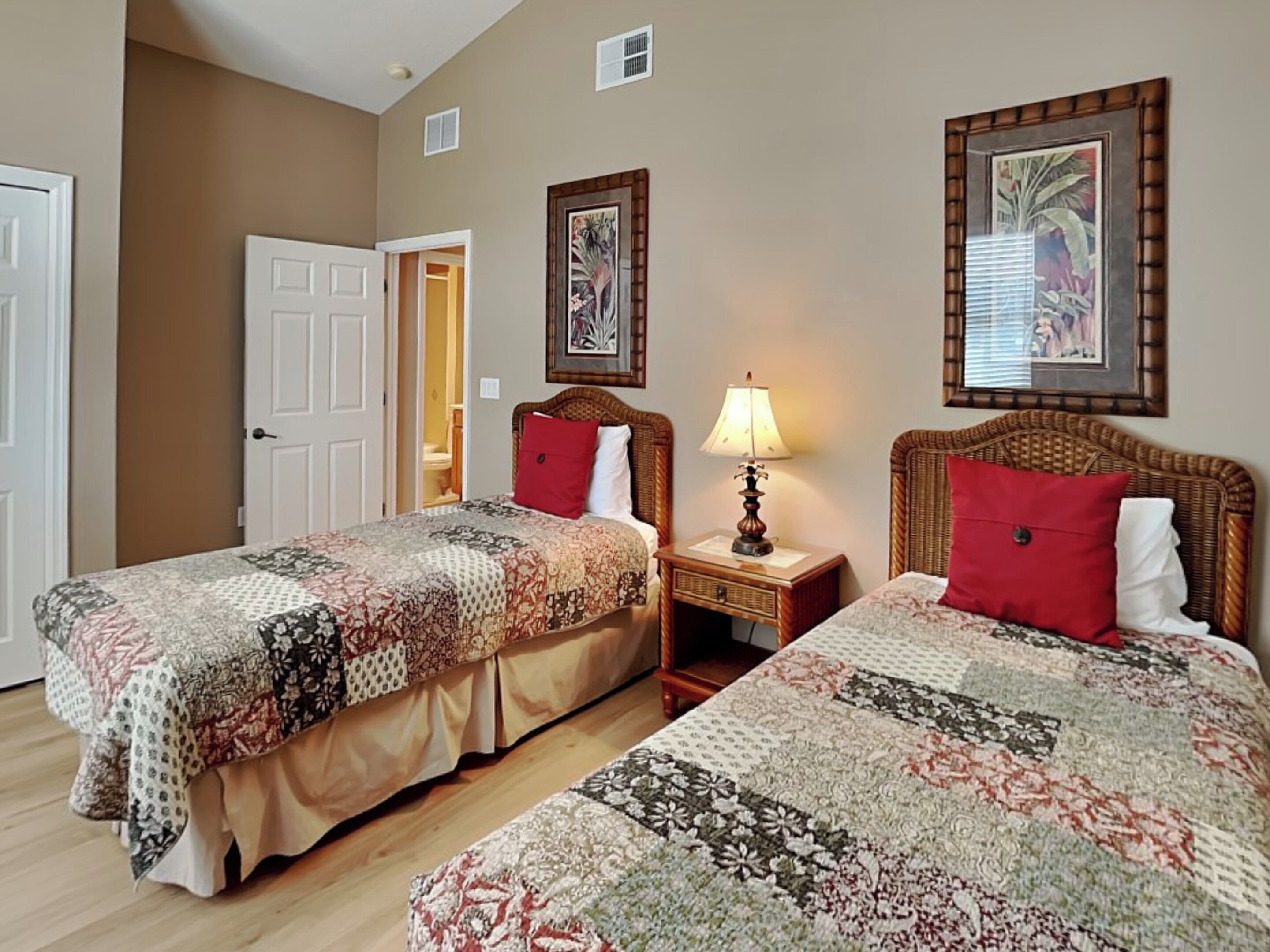 A hotel room with two beds, a nightstand, a lamp, and framed artwork on the walls.