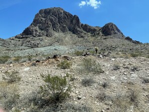 Un paysage rocheux à la végétation clairsemée, avec une montagne imposante en arrière-plan.