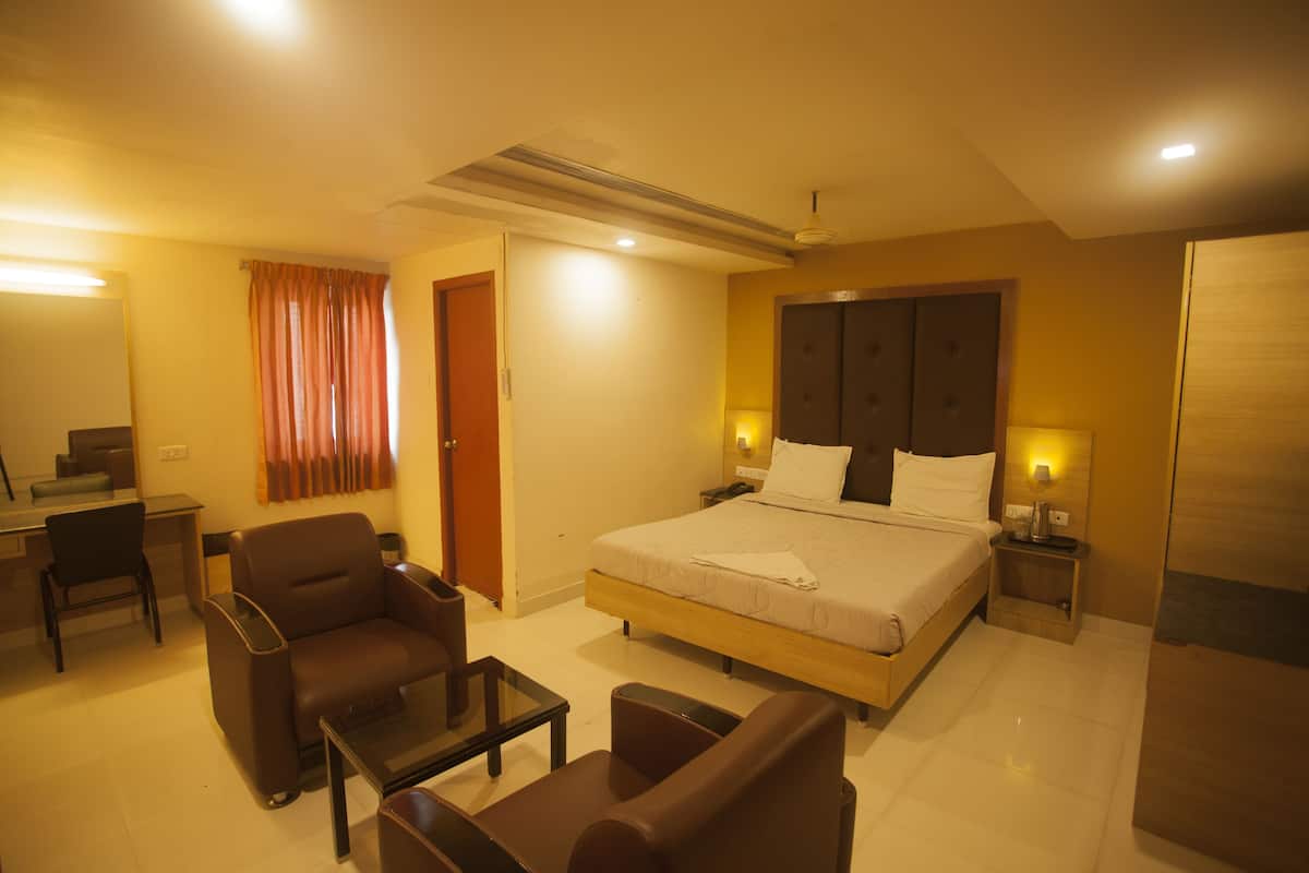 Quarto de hotel com uma cama, uma mesa, uma cadeira e uma mesinha.