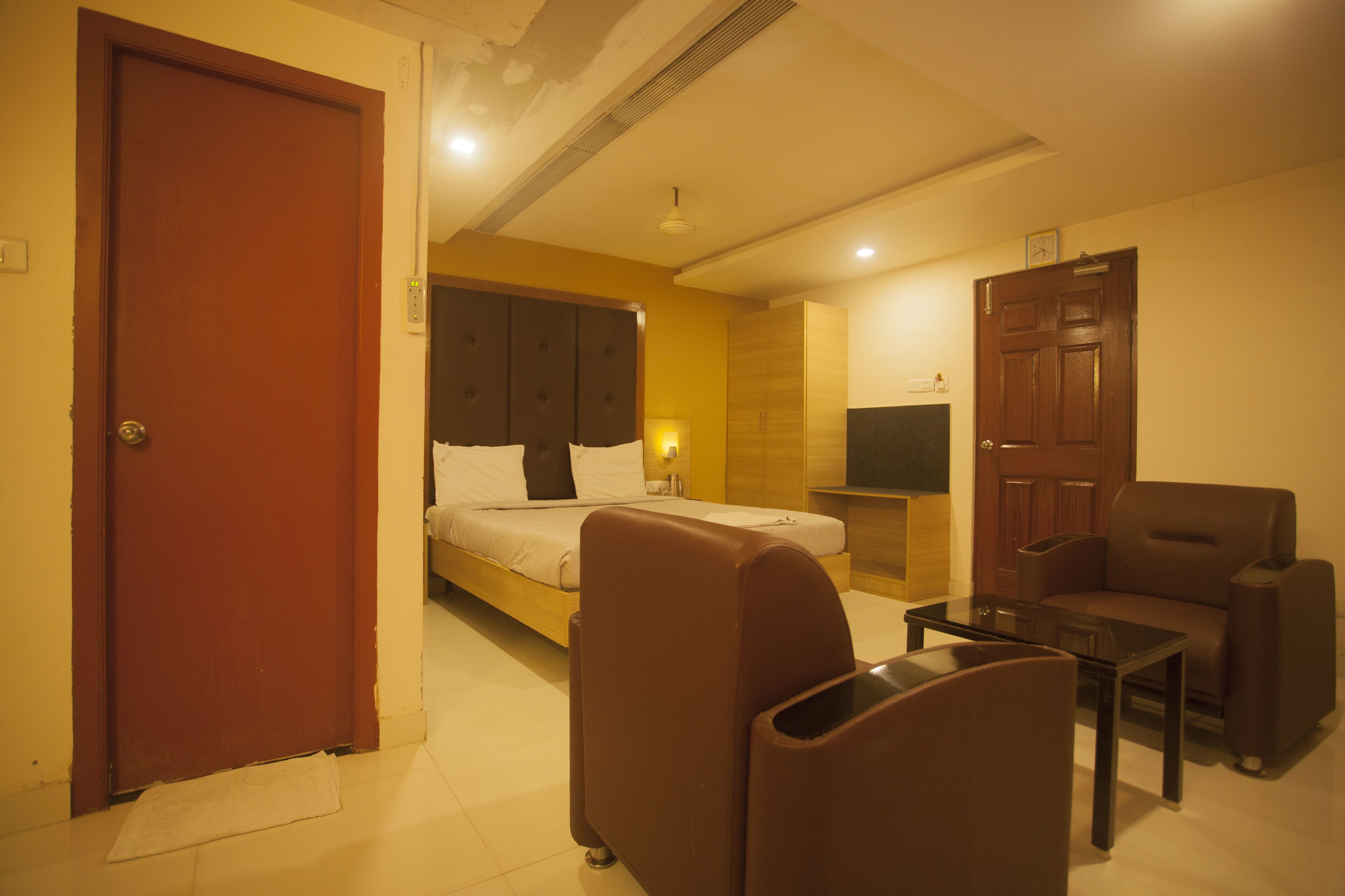 Una habitación de hotel con cama, sofá, mesa de centro y televisión.